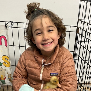 Photo of Isabel smiling while holding a duckling
