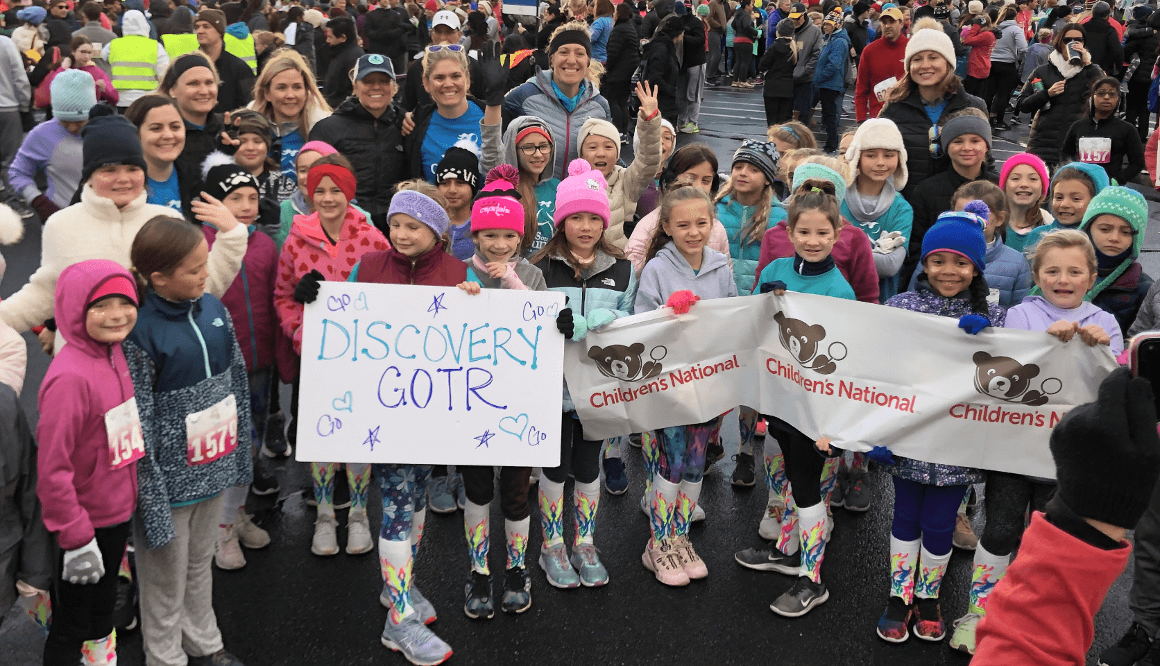 Group of children holding a Children's National sign while smiling at the camera