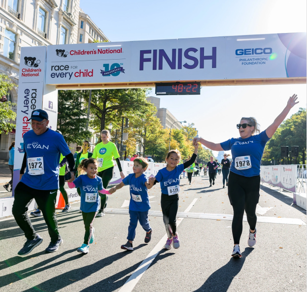 Images shows a family smiling while crossing the Race 2022 finish line togther